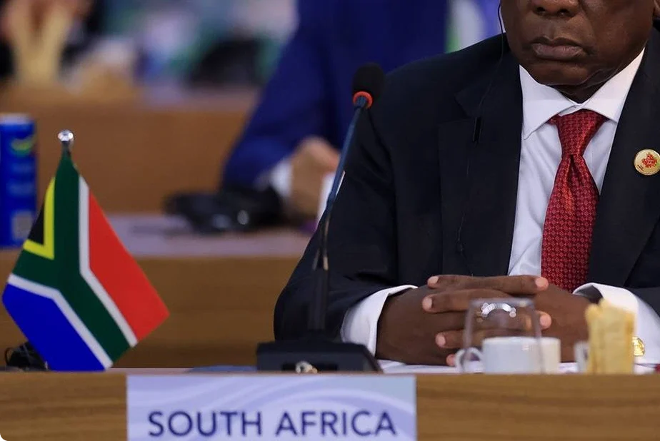 South African delegate seated at international legal conference with national flag on desk